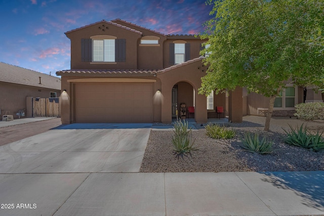 mediterranean / spanish home with stucco siding, a tile roof, concrete driveway, and a garage