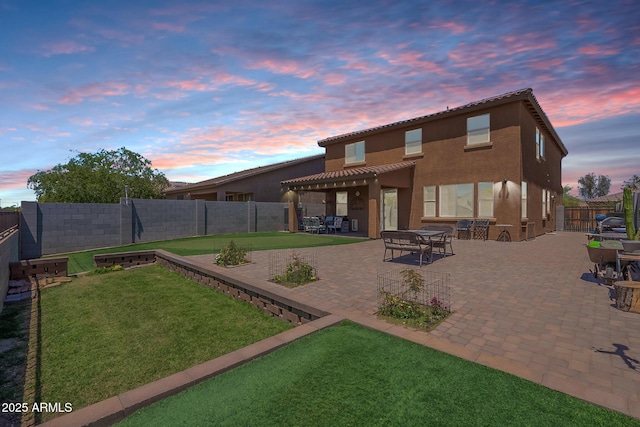 back of property at dusk with a pergola, a patio area, stucco siding, and a tile roof