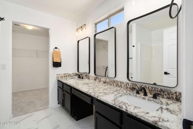 23772 W Grove St, Buckeye, AZ 85326 - bathroom with double vanity, a walk in closet, marble look tiles, and baseboards
