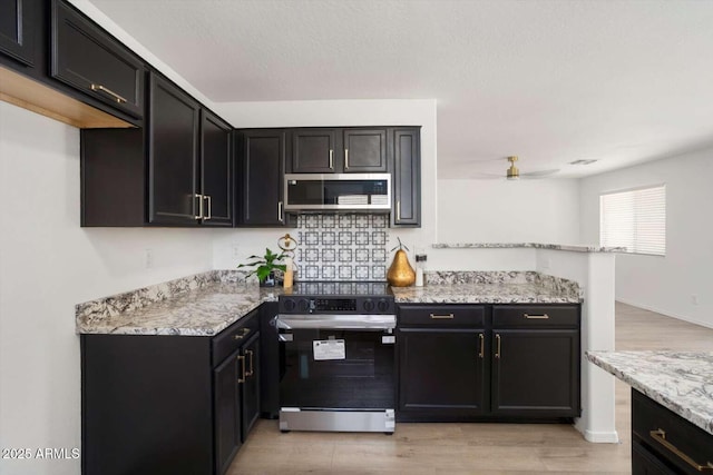 23772 W Grove St, Buckeye, AZ 85326 - kitchen featuring electric range, stainless steel microwave, light stone counters, and light wood-type flooring