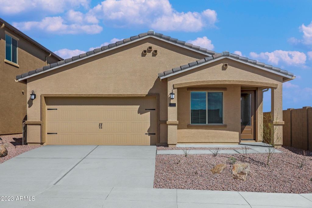 view of front facade featuring driveway, an attached garage, fence, and stucco siding