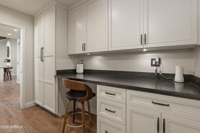 interior space with white cabinets, dark hardwood / wood-style floors, and built in desk