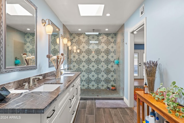 bathroom featuring an enclosed shower, vanity, and a skylight