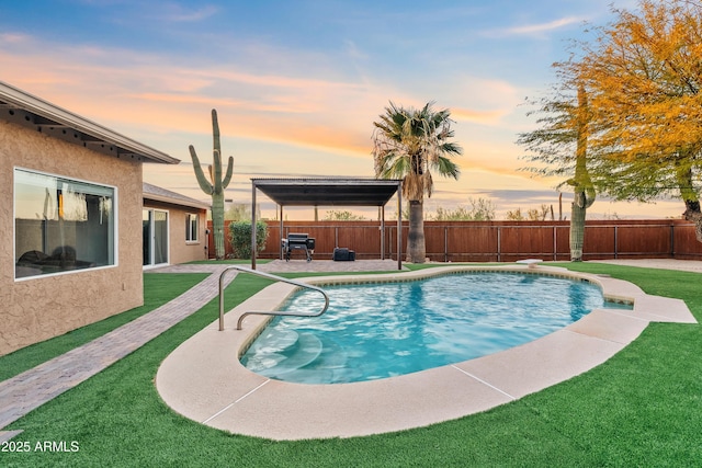 pool at dusk featuring a patio area and a yard