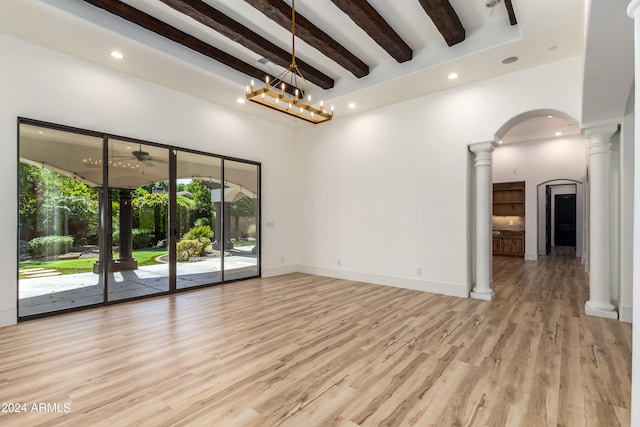 interior space with decorative columns, light hardwood / wood-style flooring, beamed ceiling, a high ceiling, and a notable chandelier