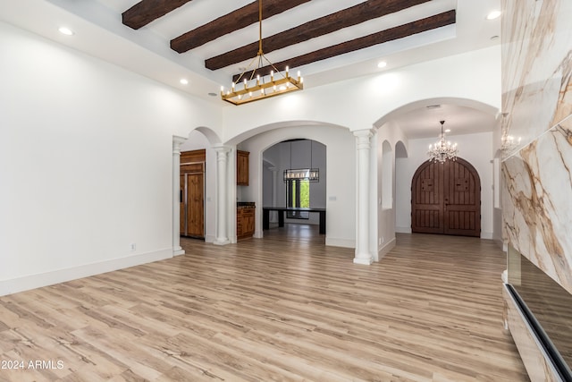 interior space featuring beam ceiling, decorative columns, a high ceiling, and light wood-type flooring