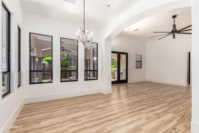 spare room with french doors, ceiling fan with notable chandelier, and light hardwood / wood-style floors