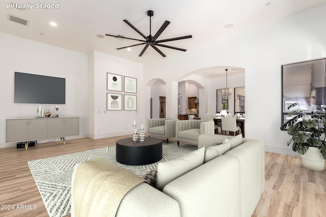 living room with light hardwood / wood-style flooring and ceiling fan with notable chandelier