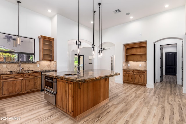 kitchen with a towering ceiling, a breakfast bar, decorative light fixtures, and sink