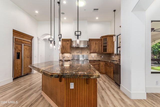 kitchen with hanging light fixtures, a breakfast bar area, appliances with stainless steel finishes, dark stone counters, and light hardwood / wood-style flooring