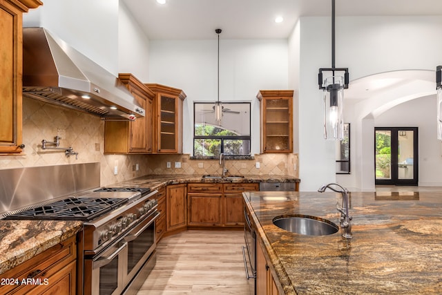 kitchen featuring wall chimney range hood, sink, a wealth of natural light, and double oven range