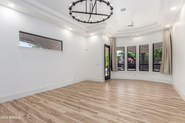 unfurnished room with light hardwood / wood-style floors, a raised ceiling, and plenty of natural light