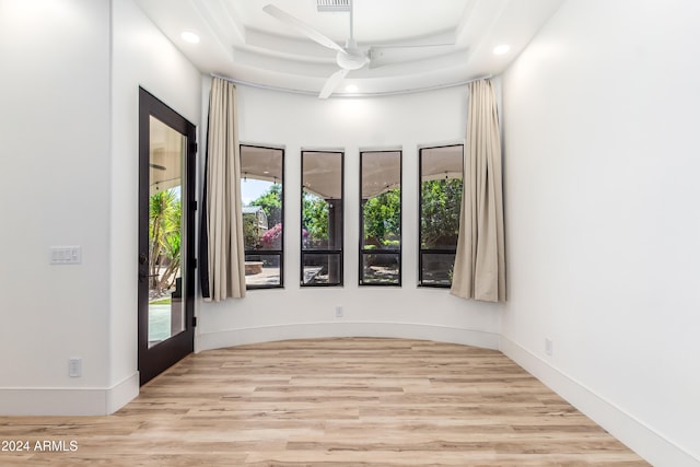 unfurnished room with a tray ceiling, light hardwood / wood-style floors, and ceiling fan