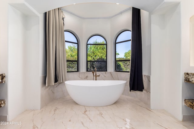 bathroom with a tub and tile walls