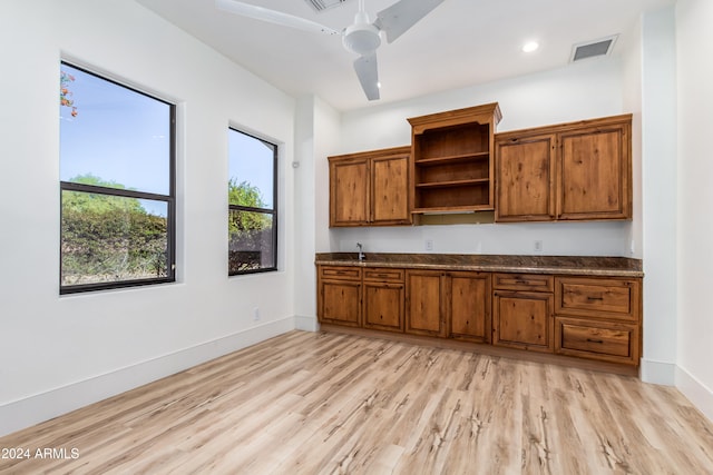 kitchen featuring light hardwood / wood-style flooring, dark stone counters, and ceiling fan