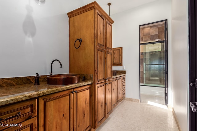 kitchen with light colored carpet, decorative light fixtures, stone counters, and sink