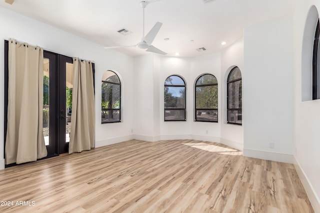 empty room with ceiling fan, plenty of natural light, and light hardwood / wood-style floors