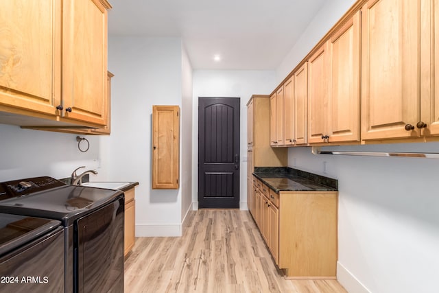 kitchen featuring dark stone counters, sink, light wood-type flooring, light brown cabinetry, and washing machine and dryer