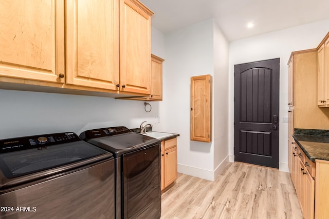 washroom with sink, washer and dryer, cabinets, and light hardwood / wood-style flooring