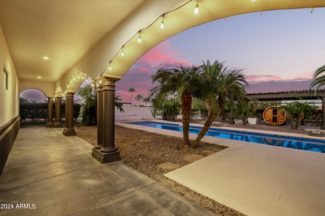 pool at dusk with a patio area