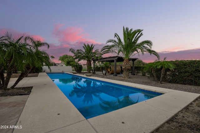 pool at dusk with a patio area