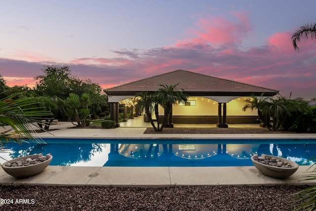 pool at dusk with a gazebo and a patio area