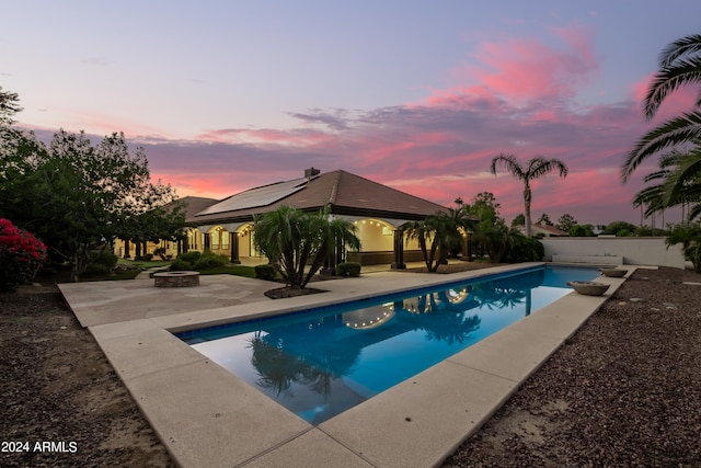 pool at dusk featuring a patio, a gazebo, and an outdoor fire pit