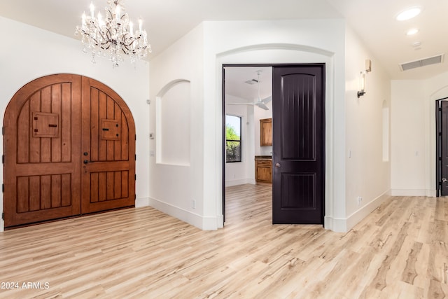 foyer entrance with lofted ceiling, light hardwood / wood-style flooring, and a chandelier