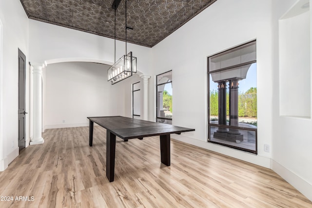 rec room featuring a high ceiling, ornate columns, and light wood-type flooring