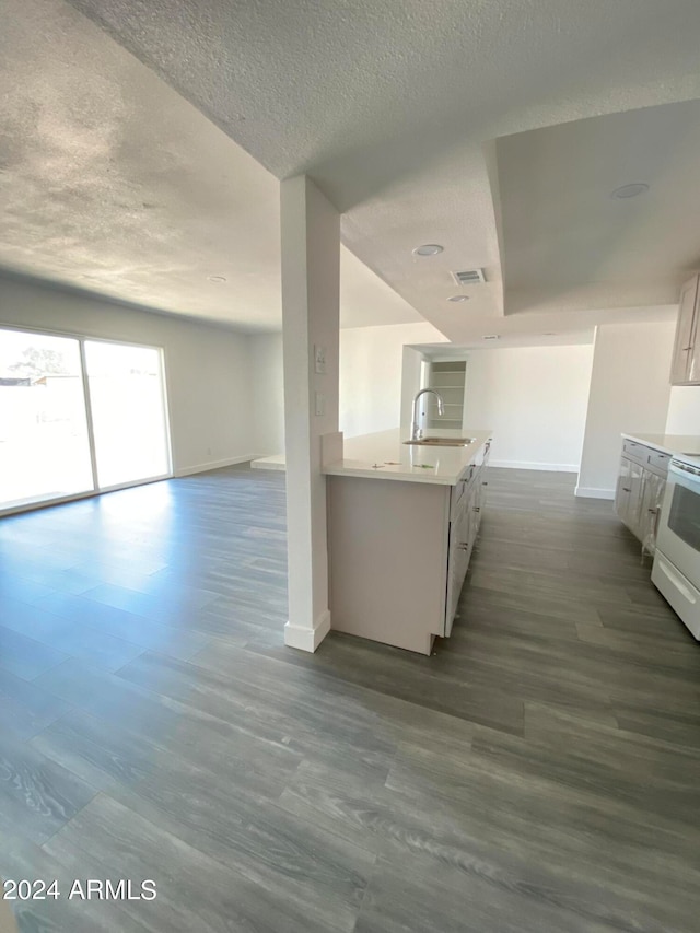 kitchen with white cabinetry, sink, dark hardwood / wood-style floors, white range oven, and a textured ceiling