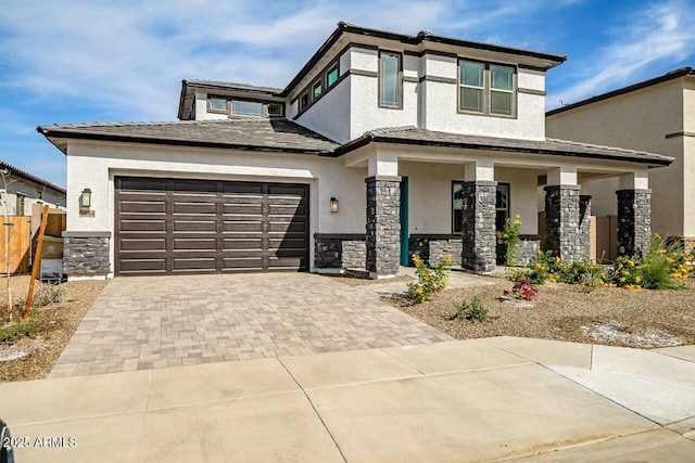 view of front of home with fence, stone siding, decorative driveway, stucco siding, and a porch