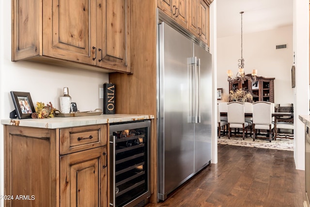 bar with built in refrigerator, a chandelier, beverage cooler, dark hardwood / wood-style flooring, and decorative light fixtures