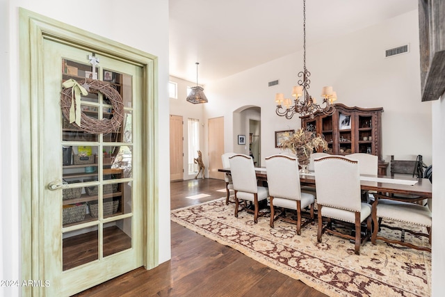 dining room with a notable chandelier, a towering ceiling, and dark hardwood / wood-style flooring