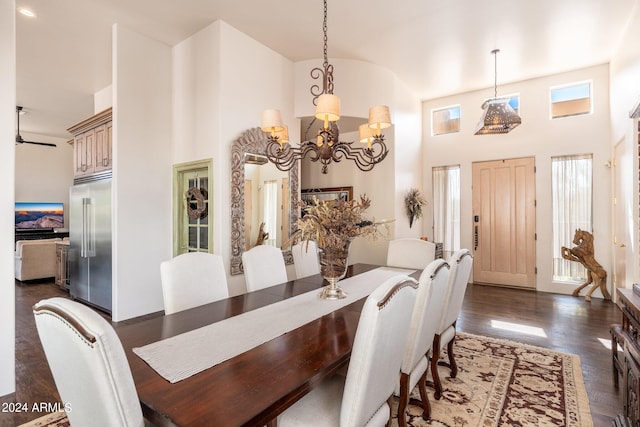 dining space featuring ceiling fan with notable chandelier, dark wood-type flooring, and a high ceiling