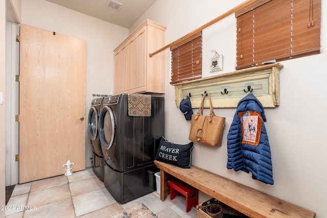 clothes washing area featuring light tile patterned floors, cabinets, and independent washer and dryer