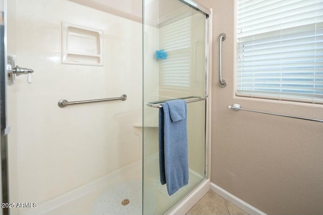 bathroom with a stall shower, baseboards, and tile patterned floors