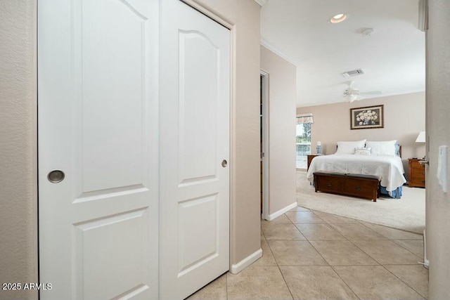 bedroom featuring light tile patterned flooring, light carpet, visible vents, baseboards, and ornamental molding