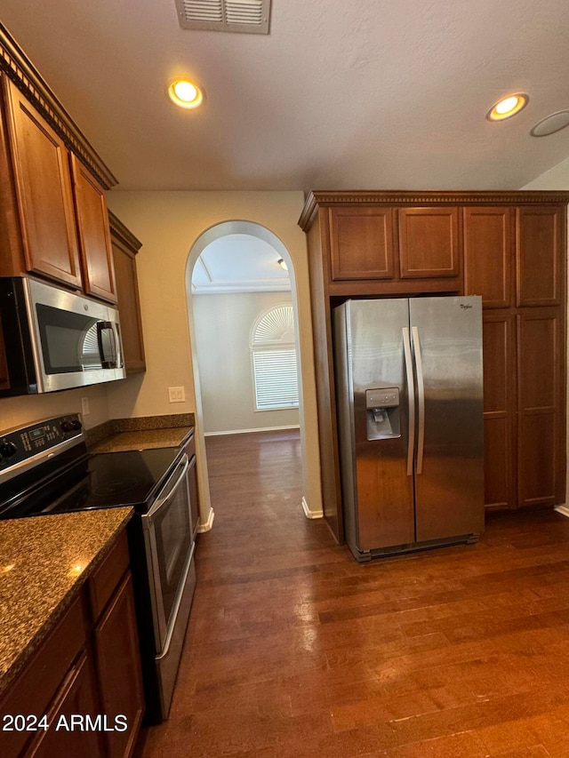 kitchen with stone countertops, dark wood-type flooring, and stainless steel appliances