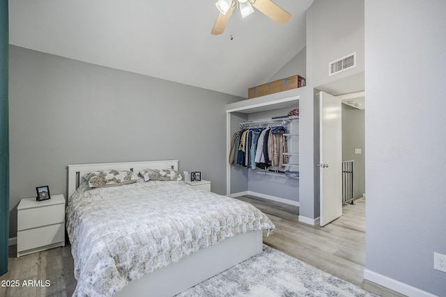 bedroom with wood-type flooring, high vaulted ceiling, ceiling fan, and a closet