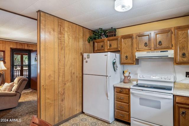 kitchen with wood walls, light carpet, and white appliances