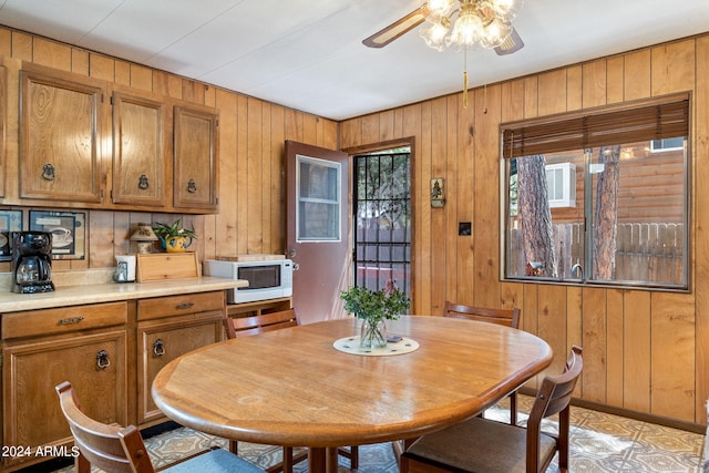 dining area with ceiling fan and wood walls