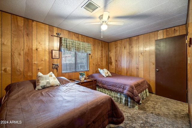 bedroom featuring carpet, wood walls, and ceiling fan