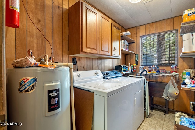 washroom with light tile patterned floors, washing machine and clothes dryer, wood walls, cabinets, and water heater