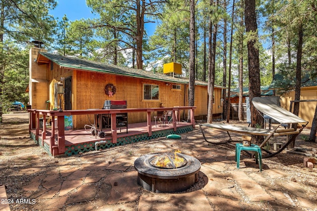 rear view of house with an outdoor fire pit and a deck