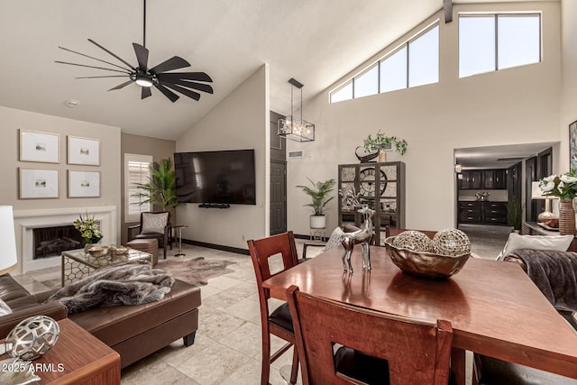 10826 E Navajo Dr, Sun Lakes, AZ 85248 - dining area featuring a fireplace, a wealth of natural light, high vaulted ceiling, and ceiling fan with notable chandelier