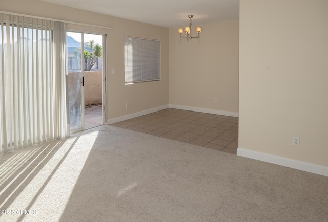 carpeted spare room with baseboards, a chandelier, and tile patterned flooring