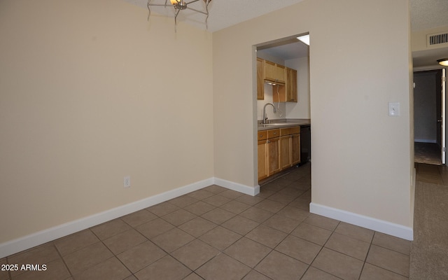 spare room with a sink, baseboards, a textured ceiling, and light tile patterned floors