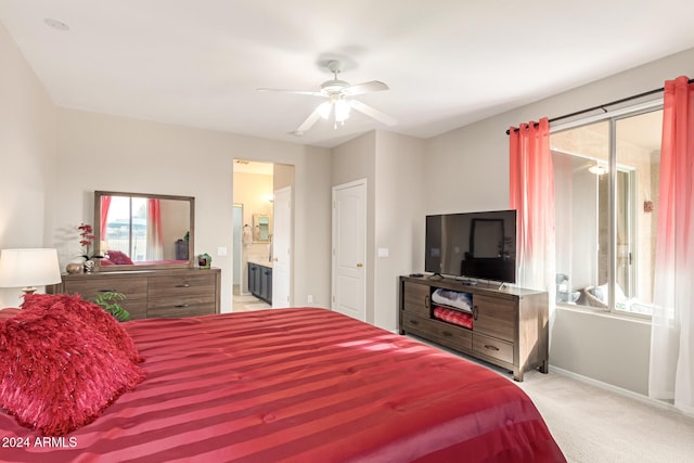 carpeted bedroom featuring ceiling fan, ensuite bath, and multiple windows