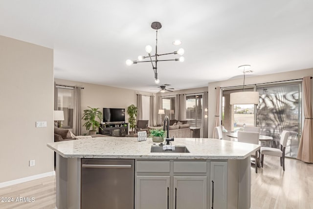 kitchen with pendant lighting, gray cabinets, sink, and an island with sink