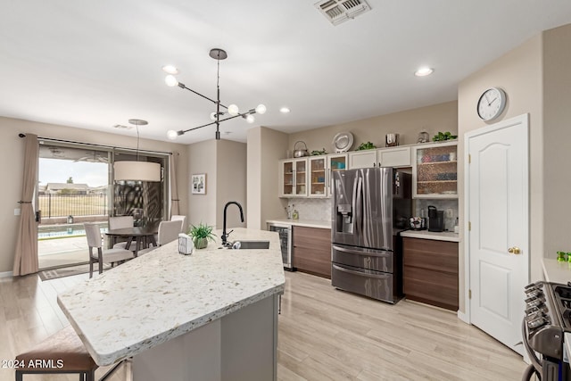 kitchen featuring hanging light fixtures, an island with sink, stainless steel appliances, and sink